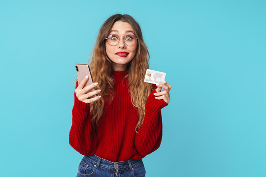 Image of surprised caucasian woman holding cellphone and credit card