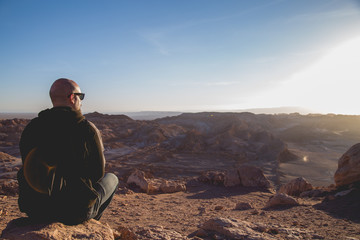 jovem sentado olhando para o horizonte em atacama 