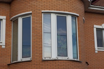 Obraz premium large white windows on the brown brick wall of the building