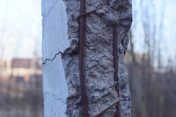part of a gray concrete broken pillar with rusty brown reinforcement rods in the street