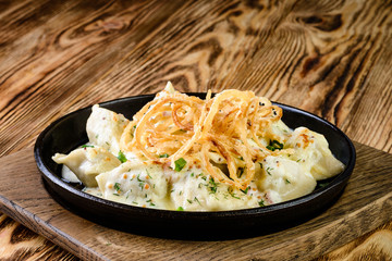 fried dumplings with onion and bacon in a pan