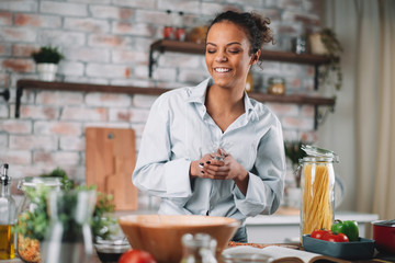 Young woman in kitchen. Beautiful mixed race woman following recipe and cooking.  