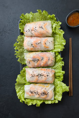 Vietnamese food spring rolls with vegetables, shrimps in rice paper on black. View from above. Asian cuisine.