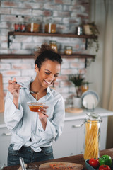 Young woman eating honey. Beautiful mixed race woman in kitchen..