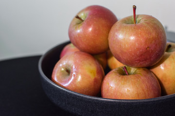 Apples in ceramic plate on the table covered black cloth