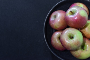 Apples in ceramic plate on the black background
