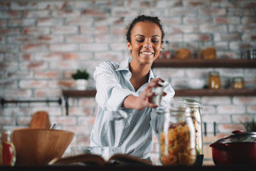 Young mixed race woman in kitchen. Beautiful woman cooking pasta. 