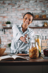 Young mixed race woman in kitchen. Beautiful woman cooking pasta. 