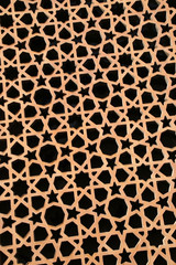 Geometric pattern made up of stars, triangles & shapes, in a gold colour against black.