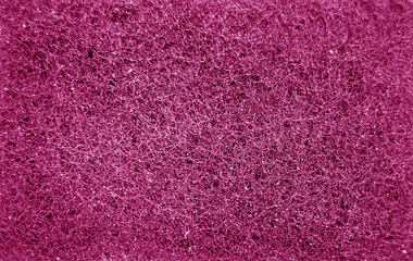 Cleaning sponge rubbing surface close up with blur effect in pink color.