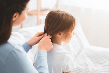 Close up of woman braiding her little daughter hair