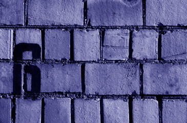 Number 6 in stencil on rusty brick wall in blue tone.