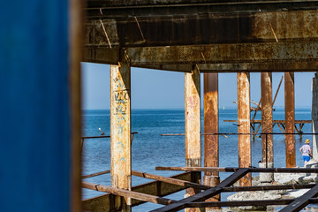 Very rusty metal frames, old thick metal subject to corrosion from salty seawater. Red bright color in sunlight