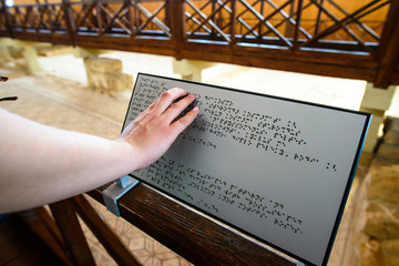 blind woman reads text on a braille sign for the blind
