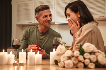 Image of man making proposal to his girlfriend during romantic dinner