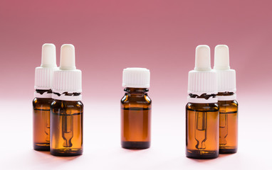 cosmetology, glass bottles with pipettes and cosmetic on a pink background