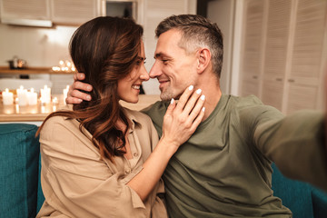 Image of couple taking selfie while having candlelight dinner at home