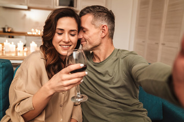 Image of couple taking selfie while having candlelight dinner at home