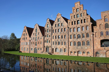 Fototapeta na wymiar Six historic brick buildings that were used as salt storehouses on the Upper Trave River next to the Holstentor (the western city gate) of Lubeck, Germany.