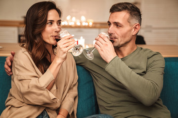 Image of couple drinking red wine while having romantic dinner at home