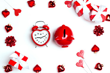 Alarm clock and piggy bank surrounded by gifts and hearts on white background. Saving money for St. Valentines Day.