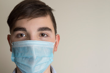 teenager in a medical disposable mask on his face on a light background. virus protection, Chinese coronavirus