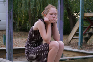 Offended girl sitting on a bench at playground