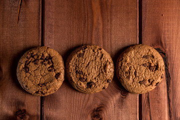 Obraz na płótnie Canvas Chocolate cookies on wooden table. Homemade chocolate chip cookies stacked in a rusting setting. Cookies with chocolate chips close-up