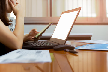 Worried businesswoman using cell phone while working on laptop at home.