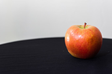 A one apple with drops of water on the black background. Macro