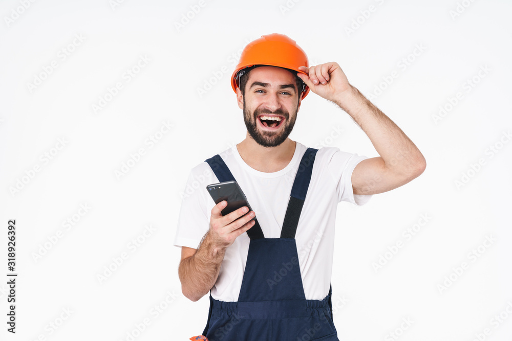 Sticker positive young man builder in helmet using mobile phone.