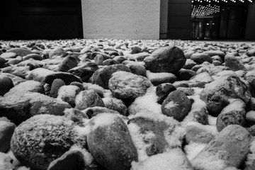 Snow covered round rock and stones. Colorful rock landscaping with snow.