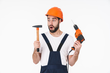Shocked young man holding drill and hammer.