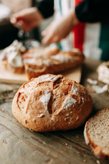  A loaf of white rye bread. Freshly baked bread. Girl's hands and cooking. Chef's table with pastries.