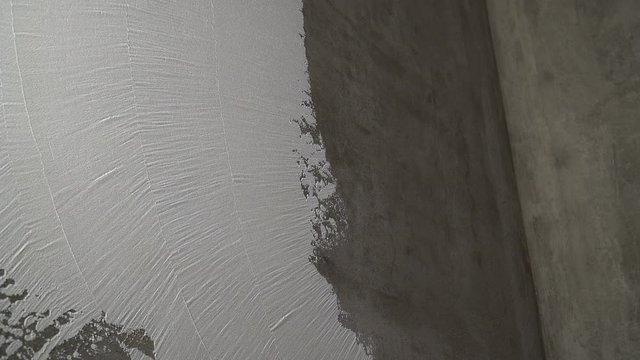 Construction worker plastering and smoothing concrete wall with putty. Putty and leveling walls for subsequent painting. Worker making repair in room. Builder using plastering tool for finishing wall