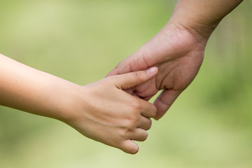 Couple holding hands with blurred nature background. Close-up