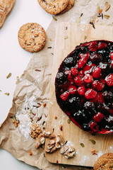 Cake on Kraft paper with cookies. Berry cake on a wooden Board. Raspberries and cherries in a pie.