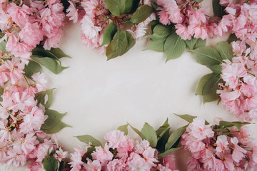 Sprigs of the sakura tree with flowers and petals on trendy marble background. Place for text. The concept of spring came. Top view. Flat lay