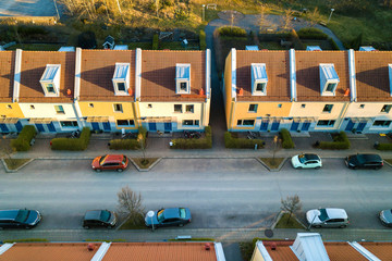 Fototapeta na wymiar Aerial view of residential houses with red roofs and streets with parked cars in rural town area. Quiet suburbs of a modern european city.