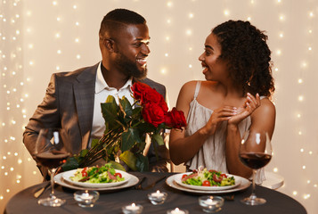 Afro guy in love giving roses to his surprised girlfriend