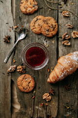 Baking on a Flatley wooden background. Oatmeal cookies with jam. Croissants with raspberry jam.