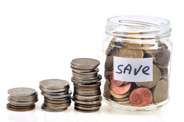 Jar of coins close up with coins stacked next to it
