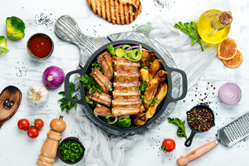 Baked pork ribs with potatoes in a pan. Barbecue. Top view. Free space for your text.