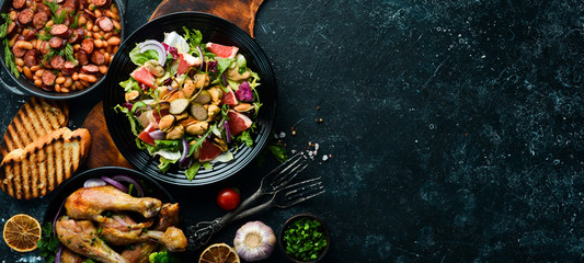 Set of dishes of meat and vegetables on black background. Top view. Free space for your text.