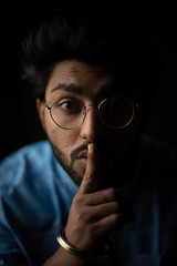 Fashion portrait of young and handsome Indian Bengali brunette man with traditional cotton wear and glasses holding pencil in black copy space background. Indian lifestyle and fashion photograph