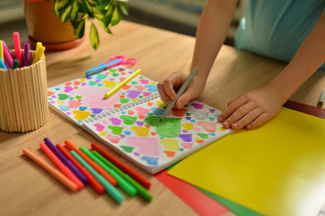  Child's hands draw hearts of different colors in a notebook. Close-up photo.