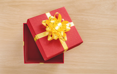Open red gift box with gold bow on wood table. Christmas and New Year's Day. Top view