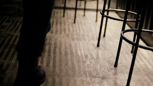 Young woman legs wearing black leather boots walking in the restaurant near bar chairs. Leather woman boots in the restaurant interiror.