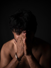 Portrait of young and handsome Indian Bengali brunette man in bare body crying loudly in black copy space background. Indian lifestyle and fashion photography