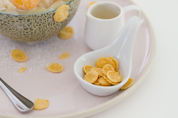 Cereal corn flakes in white blow putting near a dish of dessert, sweet food topping and menu concept.